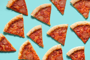 Many slices of delicious pepperoni pizza on turquoise background