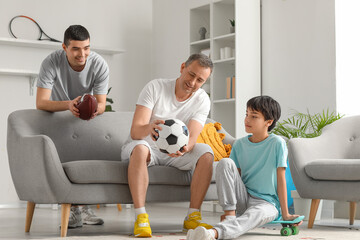 Sporty little boy with his dad and grandfather at home