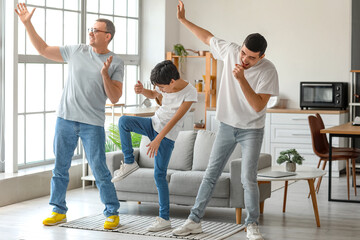 Happy little boy with his dad and grandfather dancing at home