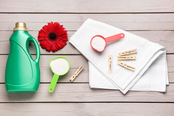 Laundry detergents, gerbera flower, clothespins and towel on wooden background