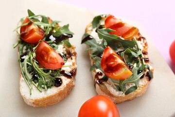 Board of tasty sandwiches with cream cheese, arugula and tomatoes, closeup