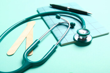 Stethoscope and notebook on turquoise background