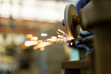 Professional metal work worker sharpening and grinding metal pipe. Man grinds metal profile in factory.