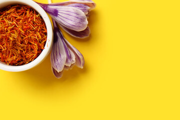 Bowl of dried saffron threads and crocus flowers on beige background