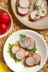 Plates with delicious radish bruschettas on wicker mat, closeup