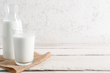 Bottle and glass with fresh milk on light wooden table