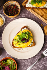 Plate with tasty scrambled eggs sandwich on grey grunge background