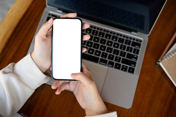 Top view image, A woman using her smartphone at a desk. A white-screen smartphone mockup.
