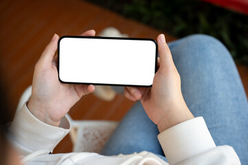 Close-up image of a woman is watching something on her smartphone while relaxing indoors.