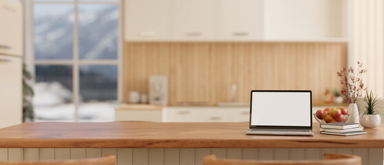 A laptop computer on a wooden kitchen countertop or island in a modern, Scandinavian kitchen.