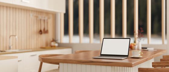 A laptop computer on a wooden kitchen countertop or island in a modern, Scandinavian kitchen.