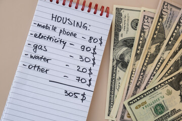 Dollar cash money with notebook handwritten housing expenses. Counting bills for electricity, gas,...