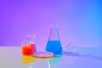 Close-up of red, pink and blue liquids inside glass laboratory flasks on a purple-blue gradient background. Research space for advertising. Copy space.