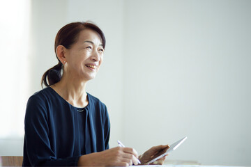 タブレット端末を使用して勉強をする日本人のシニア女性