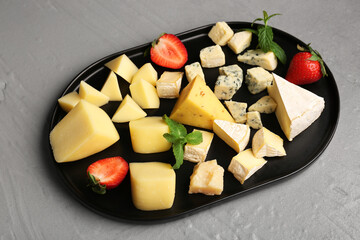 Tray with pieces of tasty cheese on grey background