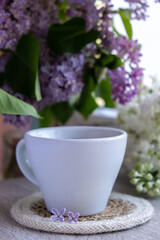 Tasty black tea in white cup on windowsill with aromatic lilac flowers. Spring composition Cup of lilac tea drinking recipe flowering branches of purple lilac. Still life for copy space greeting card