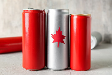 Cans of drink with maple leaf on grey table, closeup. Canadian flag concept