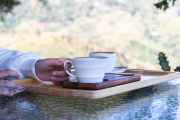 Asian women hand holding coffee cup in natural view in morning.