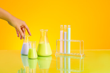 Beautiful hand model touching a conical flask of liquid. Few test tubes displayed on a rack....
