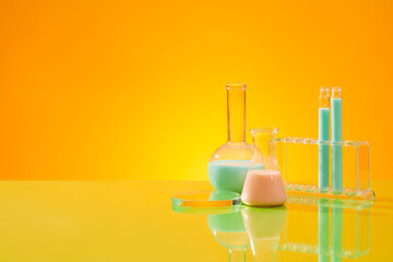 Gradient yellow background featured a glass podium, test tubes and two flask of liquid. Glamour...