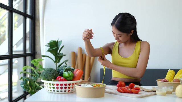An attractive Asian athletic woman eats vegetables, fruit, and salad after healthy exercise at home. Diet concept Keeping fit and eating healthy.