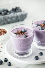 Fresh homemade blueberry smoothies topped with cacao nibs.