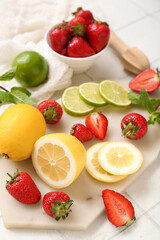 Juicer and ingredients for preparing strawberry lemonade on white tile background