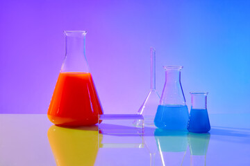 Concept laboratory tests and research natural extract making cosmetic or product. Lab equipments containing red and blue liquid decorated on gradient background with glass podium for display product