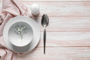 Beautiful table setting with candle and gypsophila flowers on color wooden background