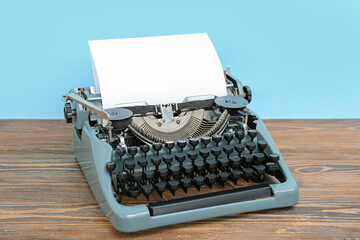 Vintage typewriter on brown wooden table near blue wall