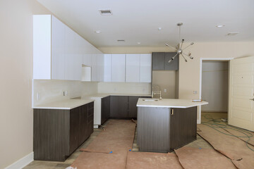 Fototapeta na wymiar Under construction is new home with custom modular kitchen comprised of cabinets an island in center.
