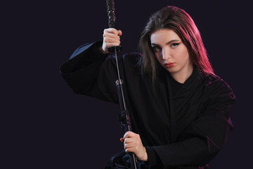 Beautiful young woman with katana on black background © Pixel-Shot