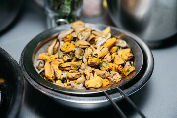 Peeled Mussels Draining in a Sieve. Fresh peeled mussels in a sieve, with their juices being drained over a bowl, capturing a step in seafood preparation.