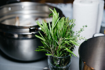 Fresh Rosemary and Thyme in Glass Jar. A glass jar filled with fresh rosemary and thyme sprigs, essential herbs for cooking, set in a kitchen environment.