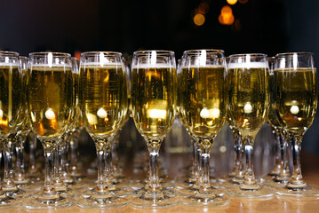 Row of Sparkling Wine Glasses on Table. Rows of filled champagne flutes, beautifully lined up on a wooden table, ready for a celebratory toast.