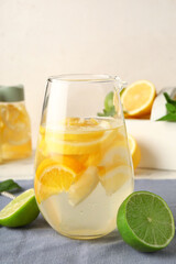 Jug of infused water with citrus fruits on light background
