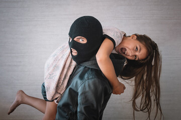 The kidnapper stole a teenage girl's child. concept of kidnapping. Terrorist and scared little hostage on white background - obrazy, fototapety, plakaty