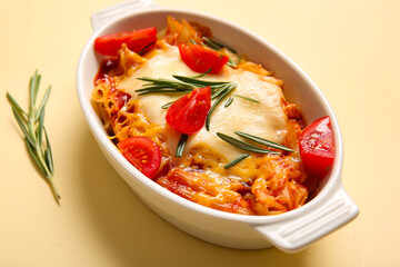Baking dish of pasta with tomato sauce and cheese on beige background