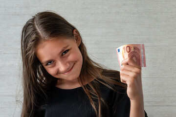 people concept - smiling teenage girl in pullover holding ten euros money banknotes over grey background