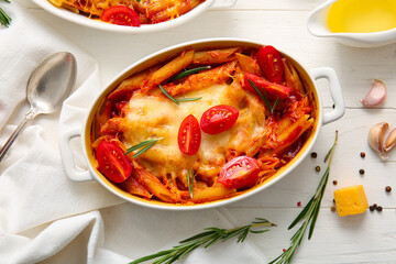 Baking dishes of pasta with tomato sauce and cheese on white tile background