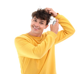 Handsome young man applying hair spray on his curly hair against white background