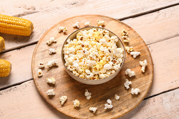 Bowl with tasty popcorn on white wooden background
