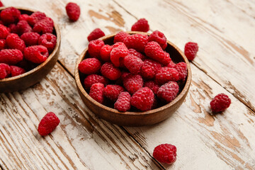 Bowls with fresh raspberry on light wooden background, closeup