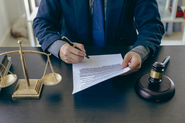 Close-up shot of lawyer working with contract documents and hammer on scales of justice, legal...