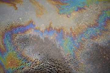 Oil stain on the asphalt, rainbow-shaped colored gasoline stains on an asphalt road