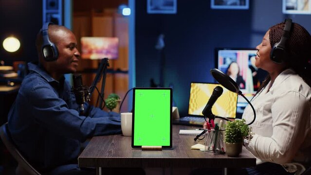 Green screen tablet in front of show host recording podcast, enjoying cup of coffee and nice conversation with guest. Mockup device in professional studio used for podcasting live session with woman