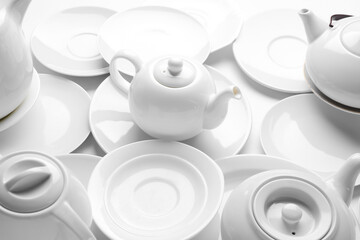 Composition with different teapots and plates on light background