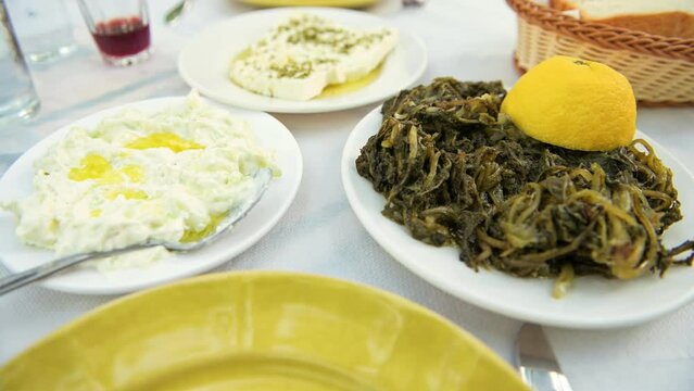 Horta wild greens with tzatziki in olive oil and feta cheese at restaurant on Ikaria island, Greece