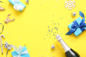 Frame made of champagne with Christmas decorations and gift boxes on yellow background