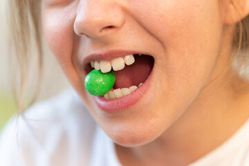 green round candy in the teeth of a young teenage girl. Addiction of sweets and candies. The harm...